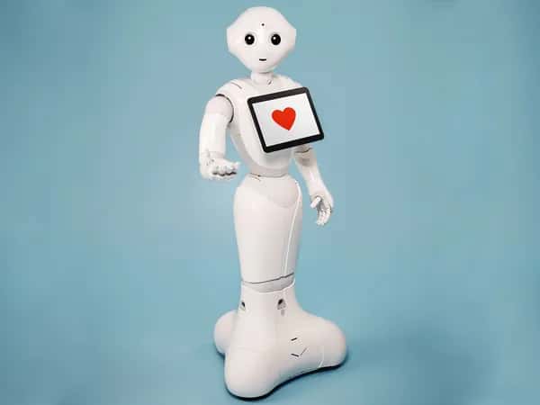 Pepper — дружелюбный белый гуманоидный робот на мобильной платформе: простое улыбающееся лицо и планшет на груди с символом красного сердца.