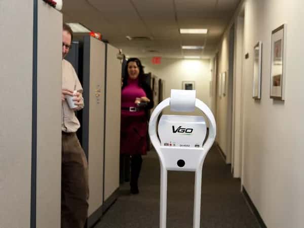 VGo — двое улыбаются роботу телеприсутствия, движущемуся по коридору офиса.