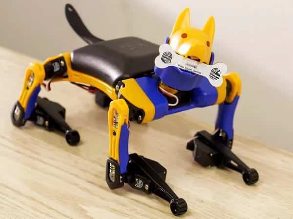 Petoi Bittle X V2 — миниатюрный робот-пёс держит в зубах деревянную кость.