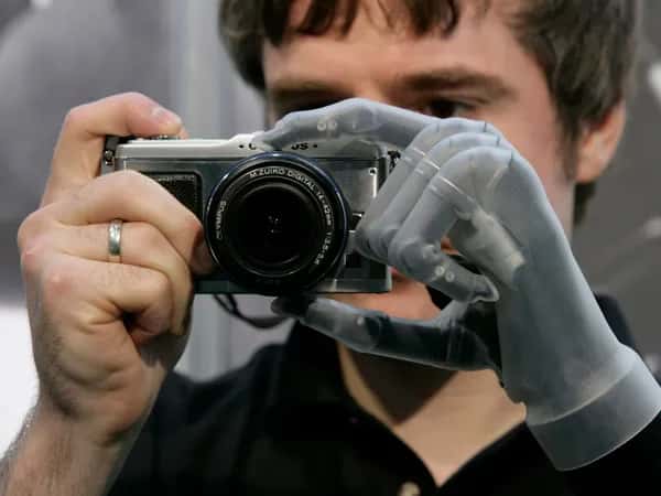 i-Limb — мужчина с протезом руки держит камеру обеими руками.