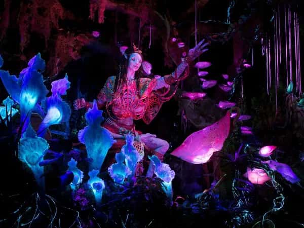 Na'vi Shaman — на цветном фото — розово-голубое освещение, в котором дружелюбный робот, похожий на инопланетянина, тянет руку к зрителю.