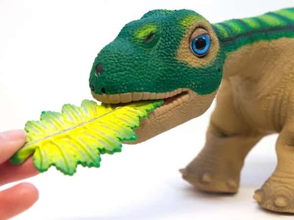 Pleo — рука кладёт игрушку в форме листа в пасть динозавра.