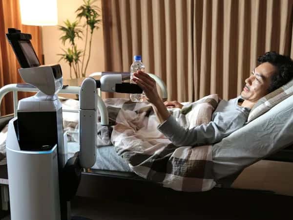 Human Support Robot — мобильный робот с захватом на одной руке подаёт бутылку воды лежачему пациенту.