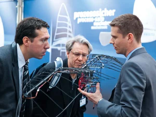 SmartBird — трое мужчин рассматривают роботизированный скелет на выставке.