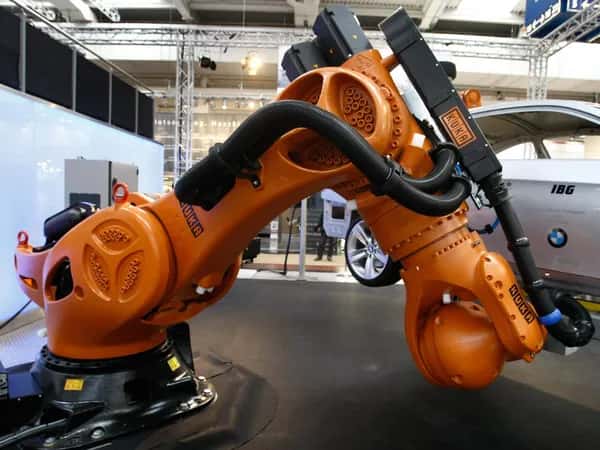 Titan — на чёрном основании установлен массивный оранжевый промышленный манипулятор, поднимающий автомобиль BMW.