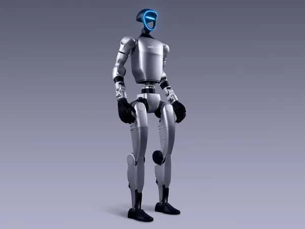 Unitree G1 — двуногий гуманоидный робот G1 от Unitree Robotics с двумя руками, оканчивающимися чёрными перчаточными кистями с пятью пальцами. Лицо в форме рамки с синей подсветкой оснащено камерами и датчиками.