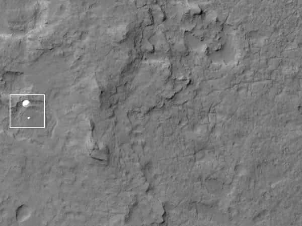 Curiosity — чёрно-белый снимок поверхности Марса: белым квадратом выделен парашют, приближающийся к земле.