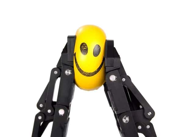 Adaptive Gripper — пара чёрных роботизированных захватов сжимает жёлтый мячик со смайликом.