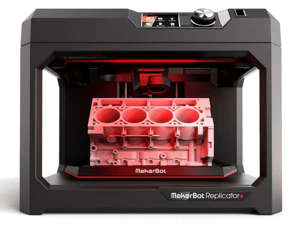 Replicator+ — коробчатая чёрная платформа с ручками удерживает розовую деталь, напечатанную на 3D-принтере.