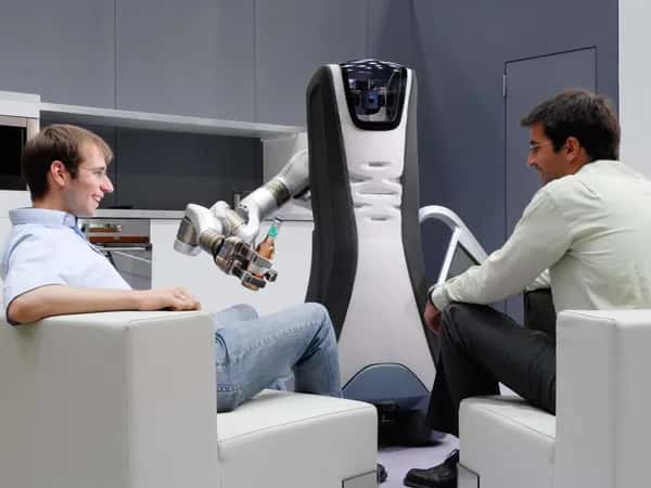 Care-O-bot 4 — робот протягивает пиво одному из двух сидящих мужчин.
