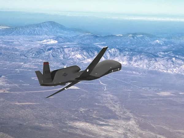 Вид на беспилотник Global Hawk UAV, летящий над пустынным ландшафтом.