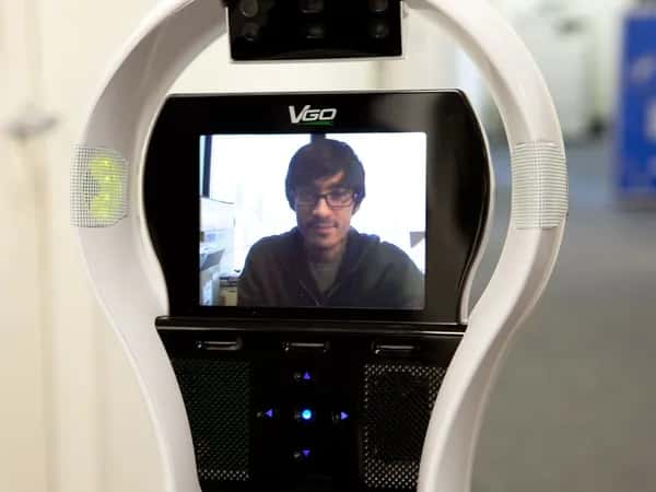 Крупный план экрана VGo — на нём темноволосый мужчина в очках.