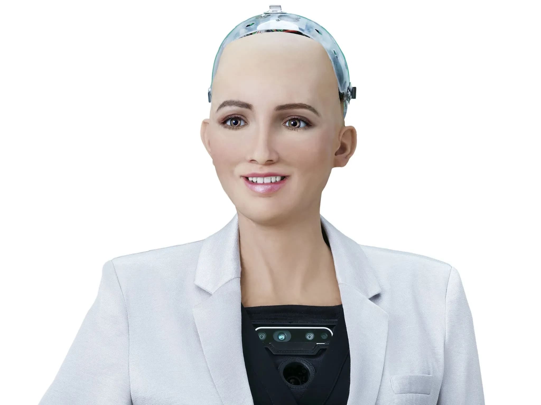 Sophia — робот с женской внешностью: реалистичная кожа персикового оттенка, зелёные глаза, тонкий нос и розовые губы с лёгкой улыбкой. Верхняя часть головы — прозрачный кожух с электроникой. Робот одет в белый пиджак поверх механического торса с чёрной панелью, оснащённой камерами и датчиками.
